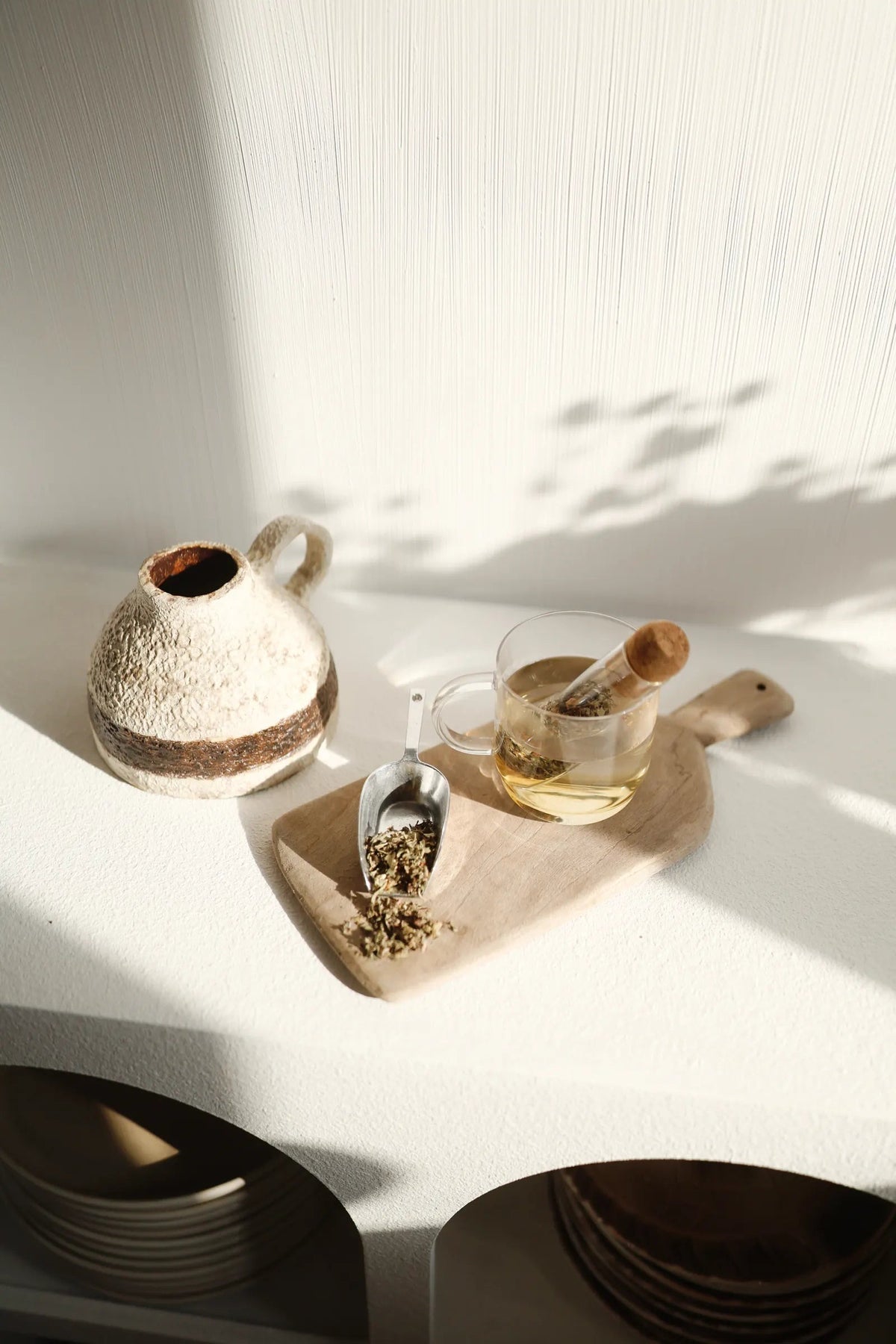 Tasse en verre, infuseur et plantes dans la lumière