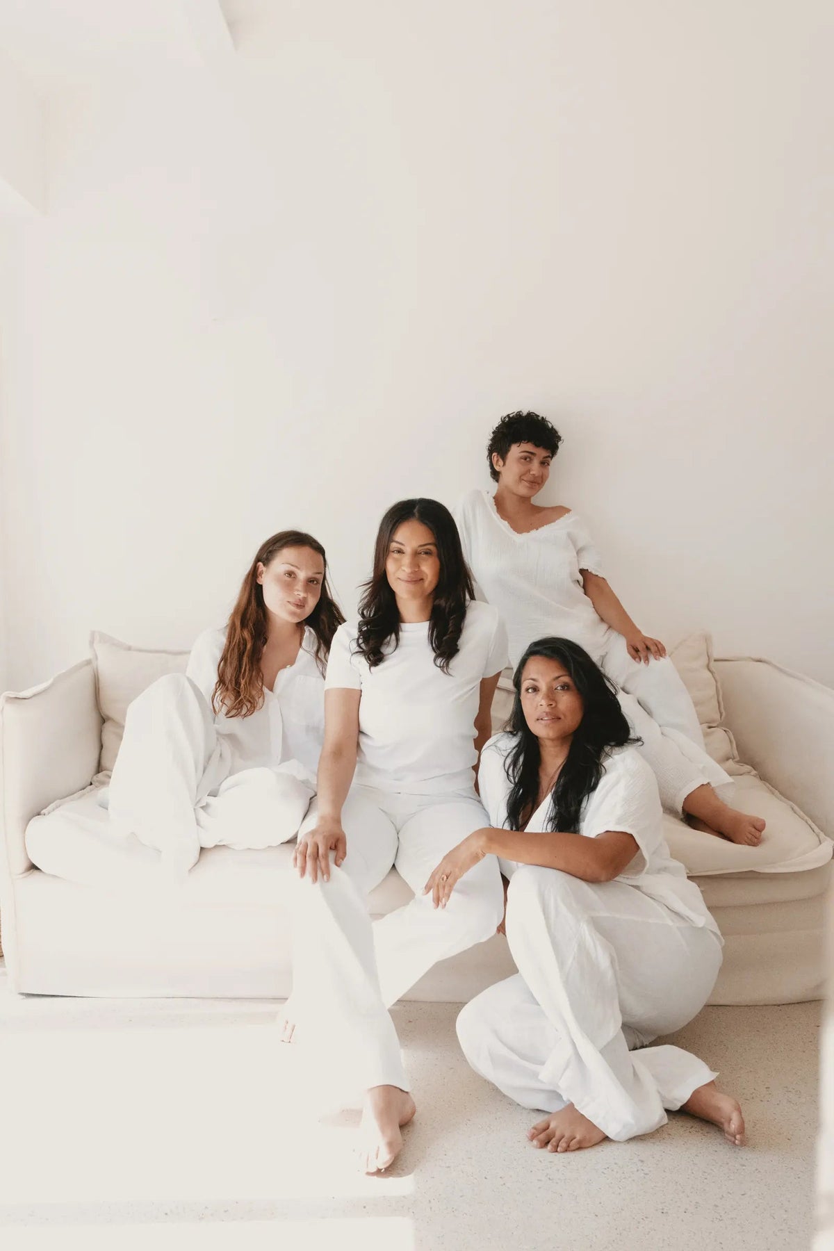 4 femmes vêtues de blanc, réunies sur un canapé